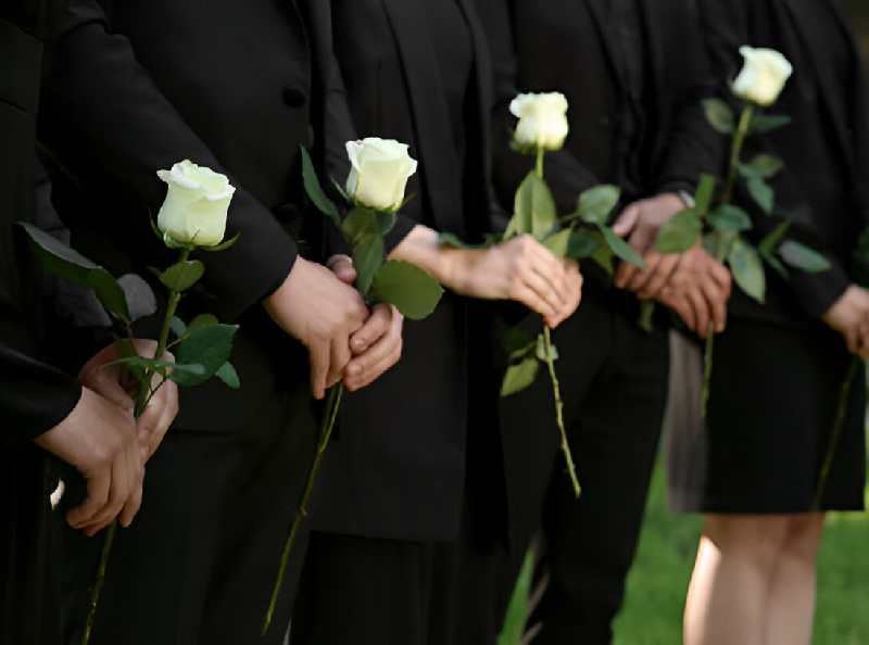 People in black clothes with white rose flowers