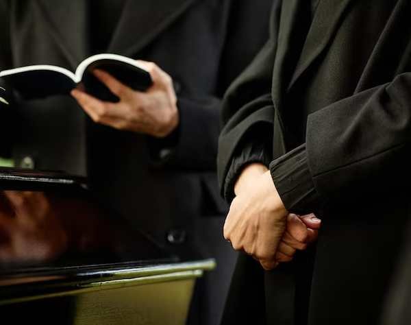 standing-by-coffin-outdoor-funeral-ceremony-priest-reading-prayer
