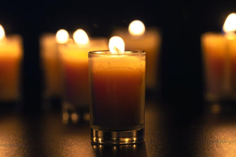 Burning candle on black background with backlight memorial day