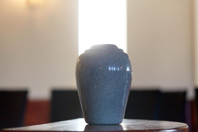 Funeral and mourning concept - cremation urn on table in church