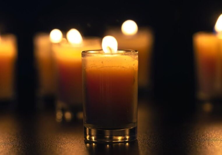 Burning candle on black background with backlight memorial day