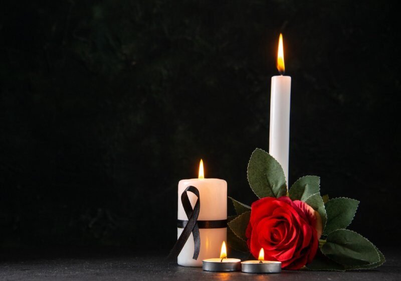 Front view of burning candles with red flower