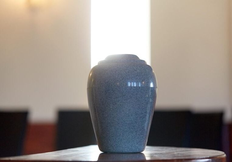 Funeral and mourning concept - cremation urn on table in church